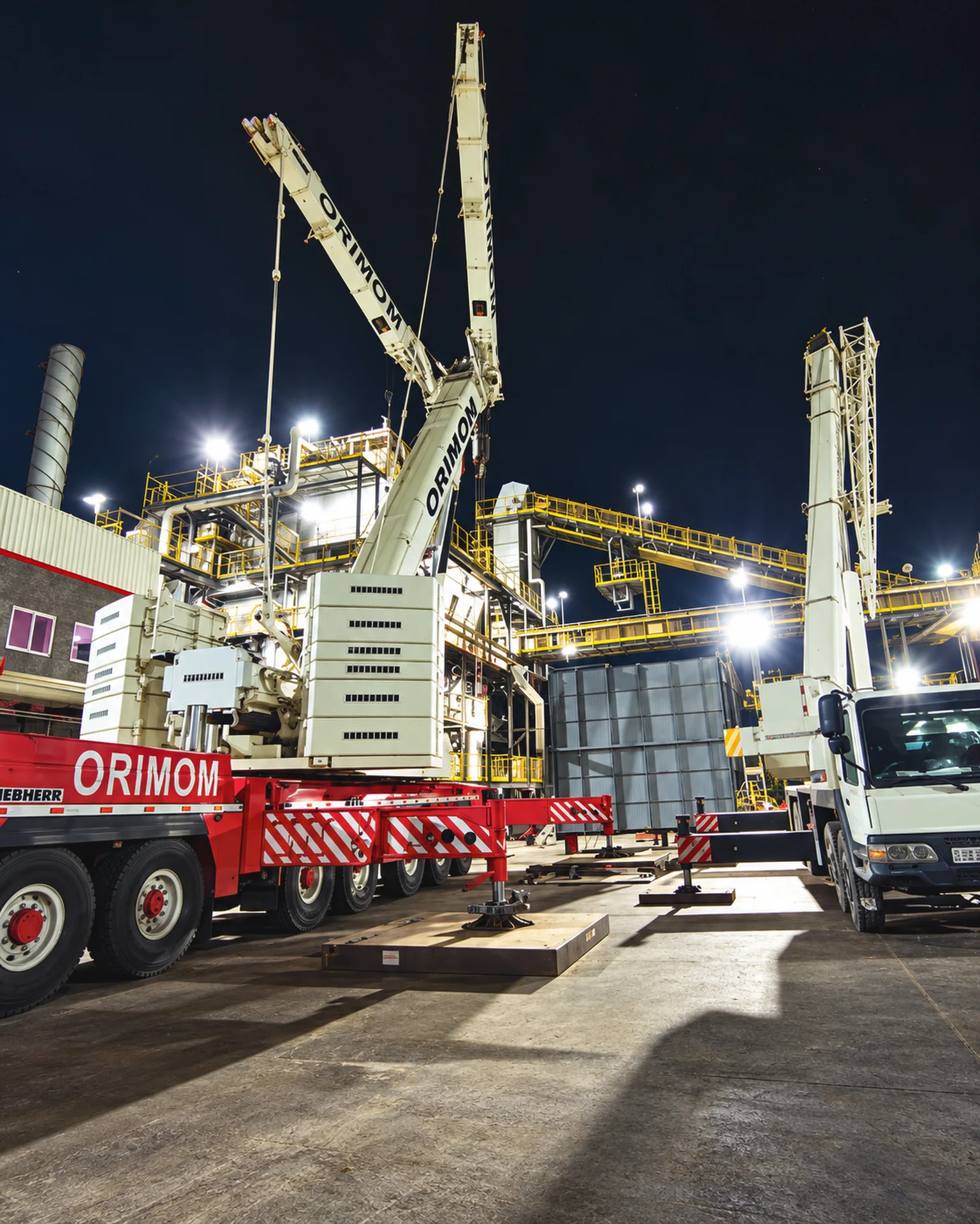 Guindastes em operação industrial noturna